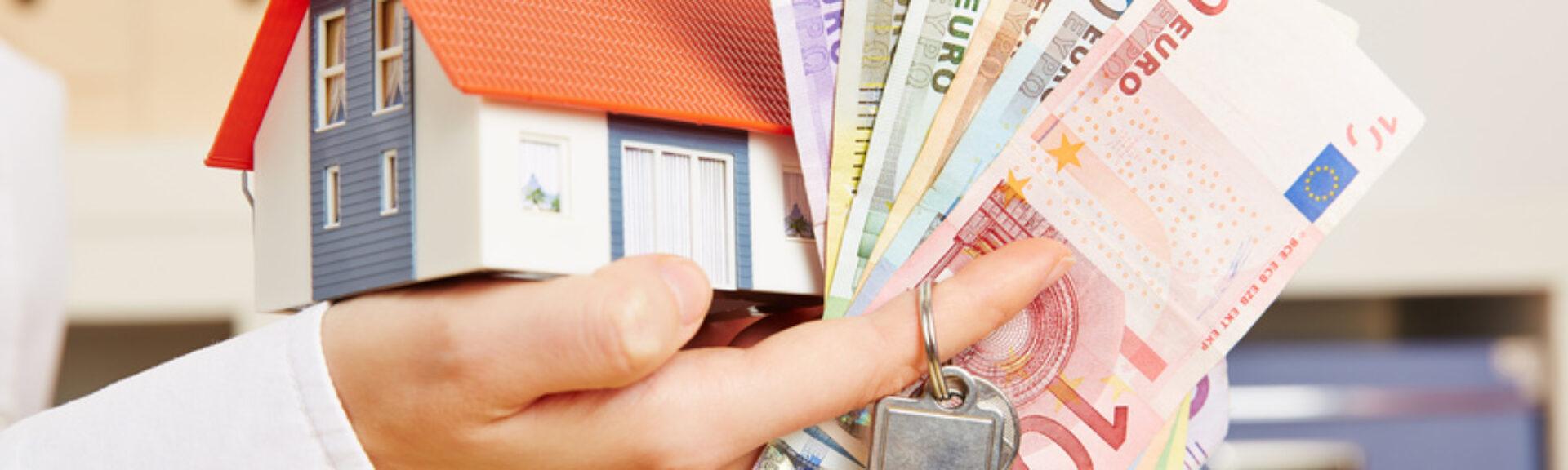Hand mit Haus und Geld und Schlüssel
