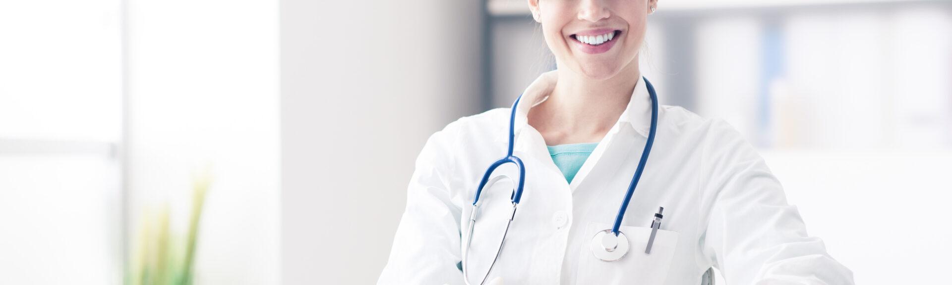 Female doctor working at office desk, she is smiling at camera, healthcare professionals