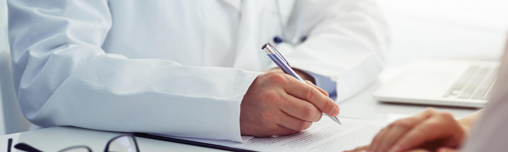 Doctor consults with his patient and writes notes on the clipboard