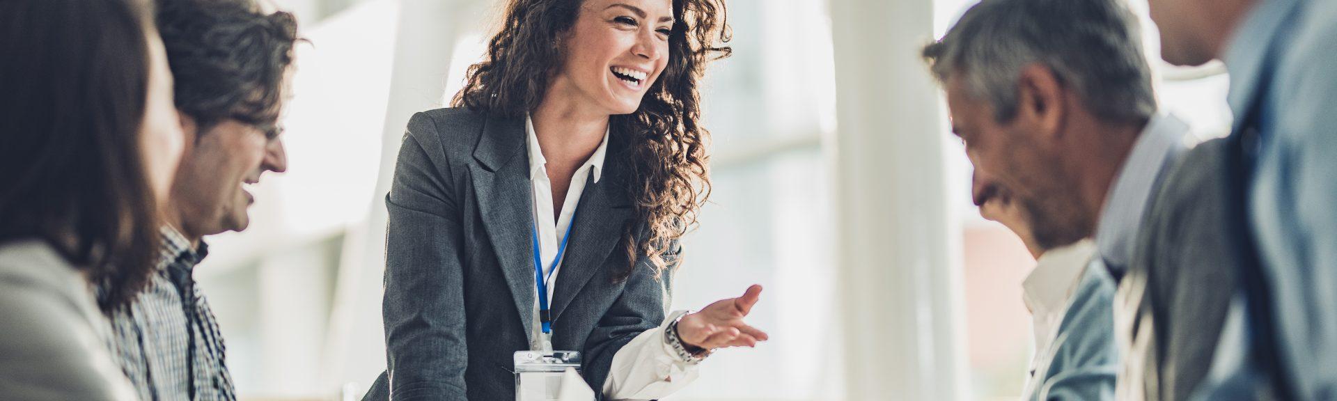 Young happy CEO communicating with her colleagues on a meeting in the office.