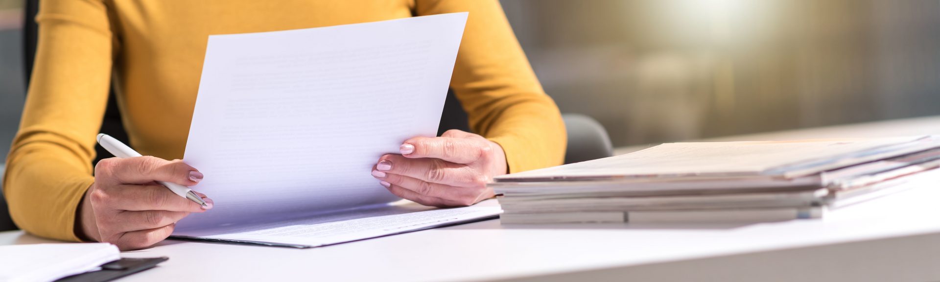 Businesswoman checking document in office, wearing yellow sweater