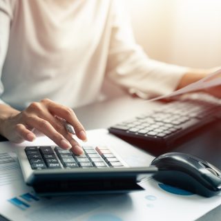 Woman accountant or banker use calculator and pen, computer, graph paper on table at office. Business and finances Saving Economy concept.