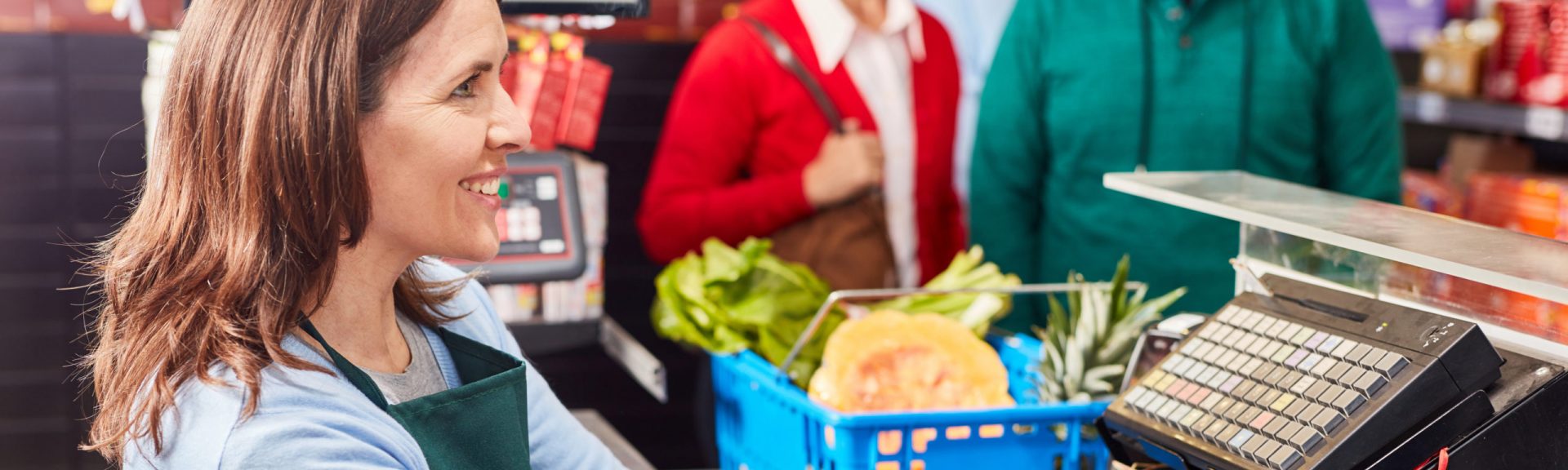 Lächelnde Kassiererin an der Supermarkt Kasse nutzt Barcode-Scanner