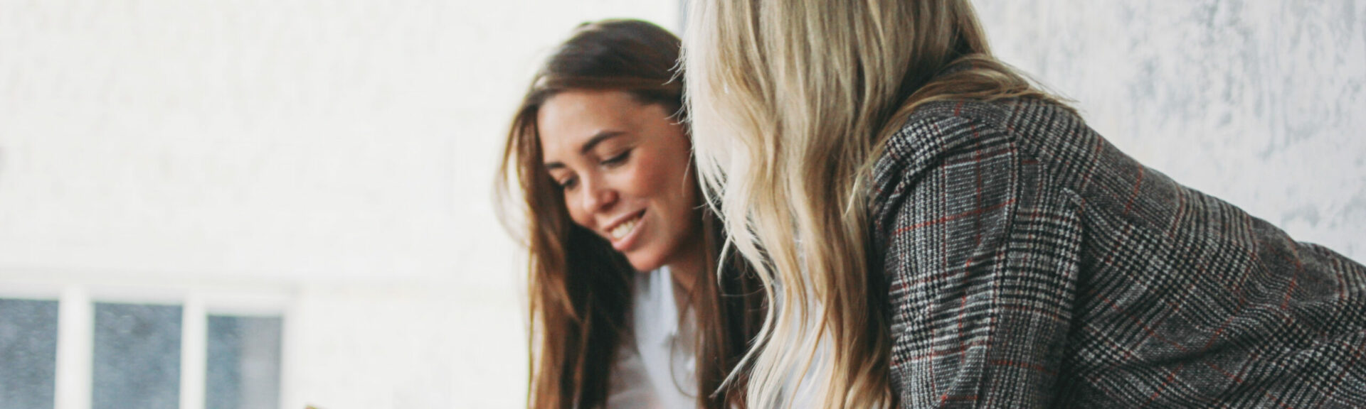 Young successful women colleagues discuss joint project, coaching or mentoring in the modern loft office