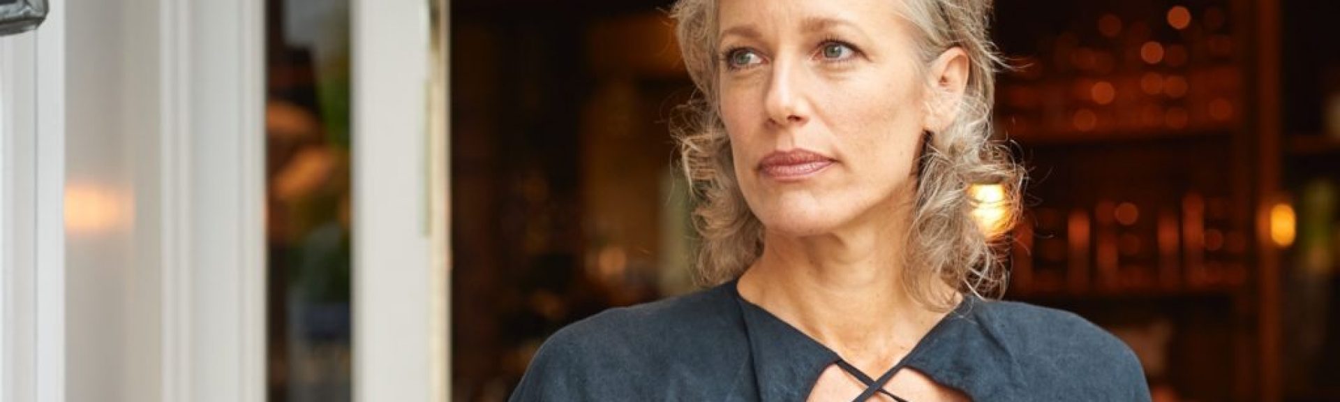 Woman with grey hair comes out of a coffeeshop