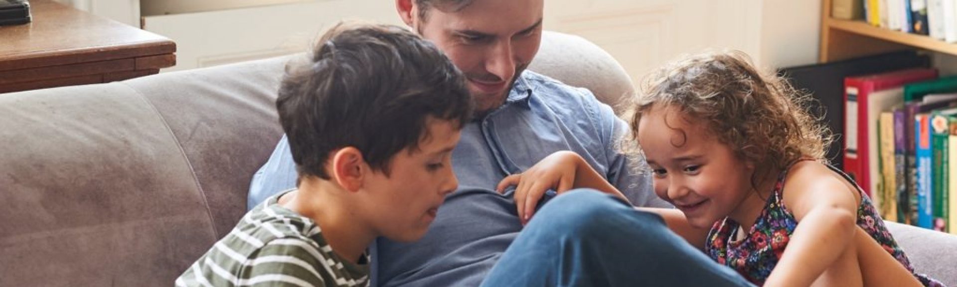Dad sitting on the couch at home with his two children