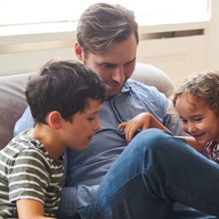 Dad sitting on the couch at home with his two children