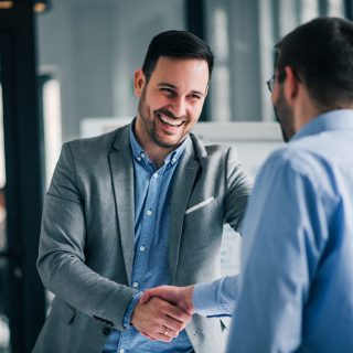 Portrait of cheerful young manager handshake with new employee.