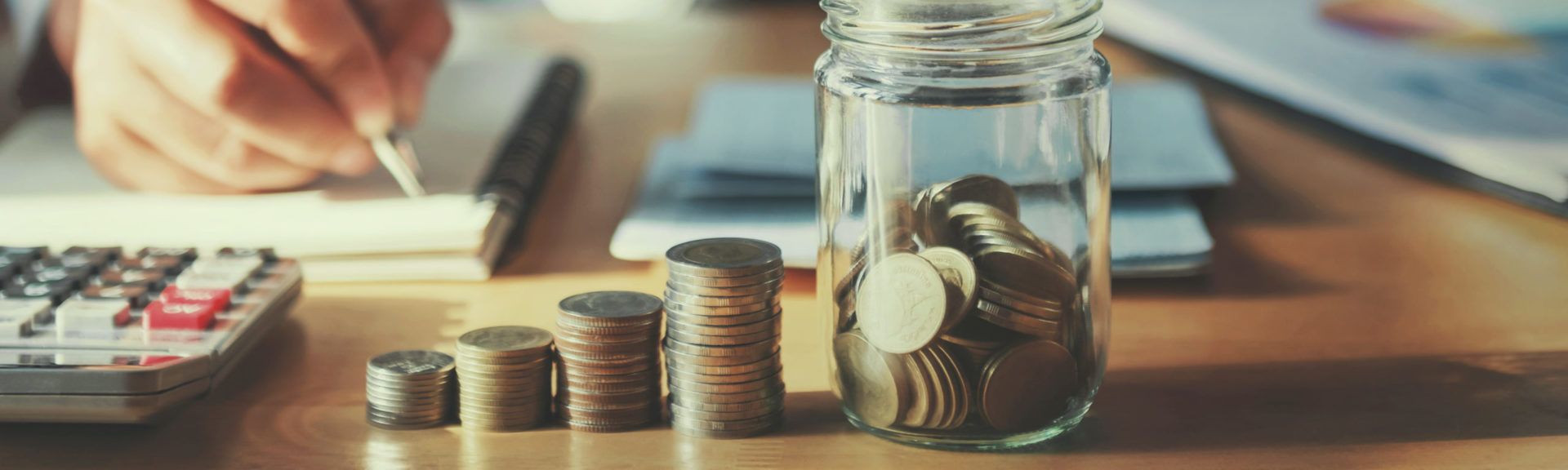 businessman saving money concept. hand holding coins putting in jug glass