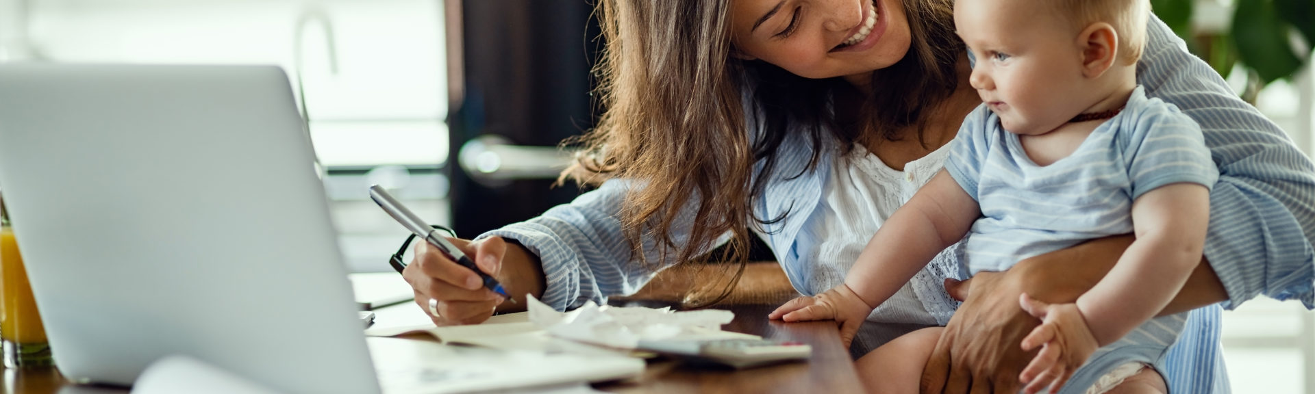 Young happy mother going through home finances and communicating with her baby son.