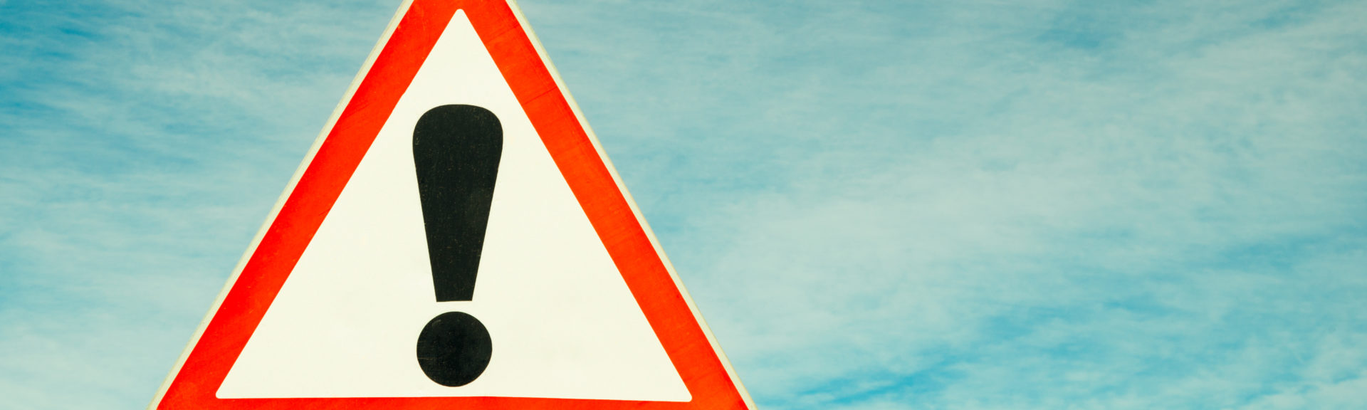 Exclamation point of attention against the sky. triangular sign. Danger, warning.