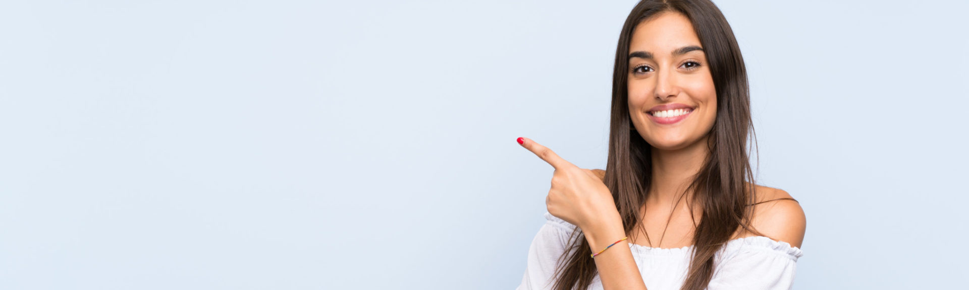 Young woman over isolated blue background pointing finger to the side