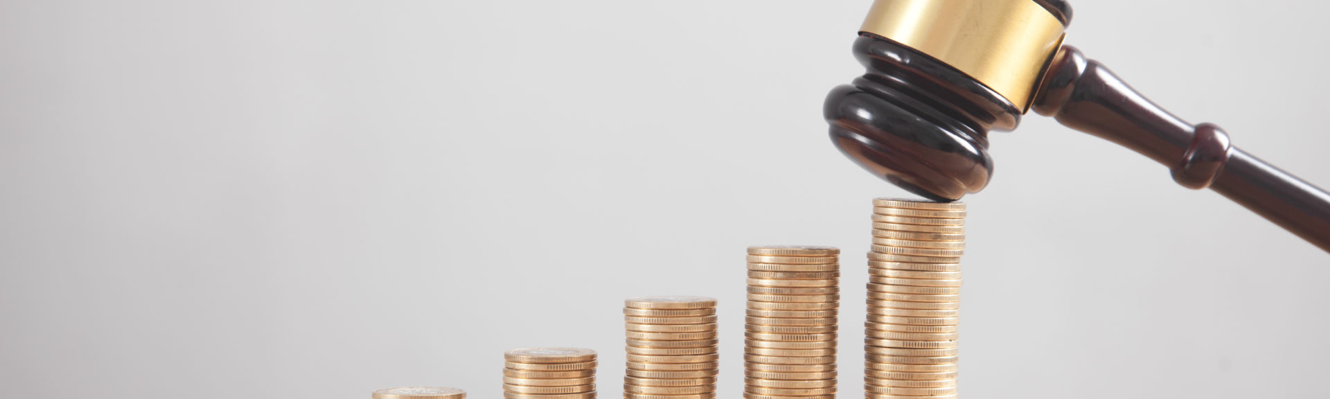 Stack of coins with judge gavel.