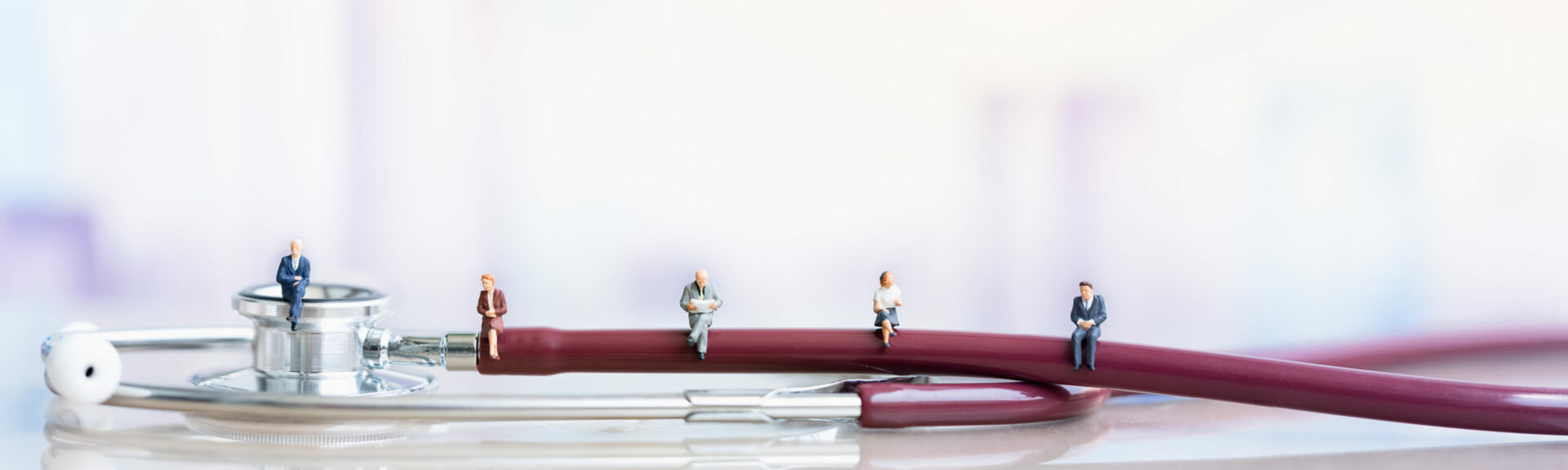 Miniature people: Elderly people sitting on Stethoscope. social security income and pensions. Health Care Inequality. Time counting down for retirement concept. Social distancing.