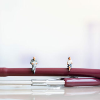 Miniature people: Elderly people sitting on Stethoscope. social security income and pensions. Health Care Inequality. Time counting down for retirement concept. Social distancing.