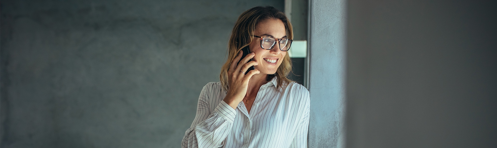 Business Woman on the phone talking, smiling while looking out of the window