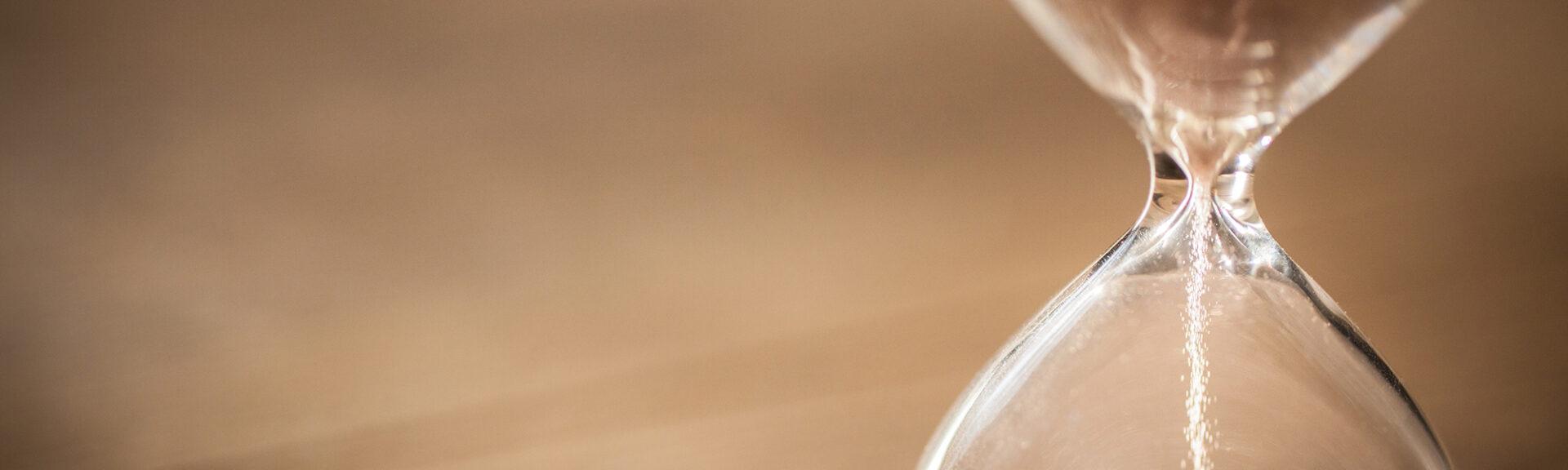 Sand running through the bulbs of an hourglass measuring the past
