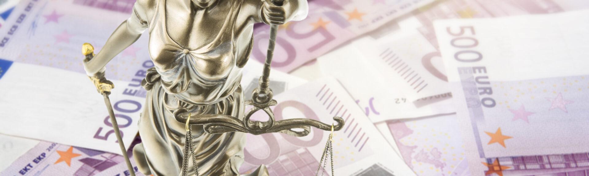 Eine goldene Justitia Figur steht auf vielen 500 Euro Geldscheinen. Konzeptionelles Bild zum Thema Gericht und Geld. Lens Flares.