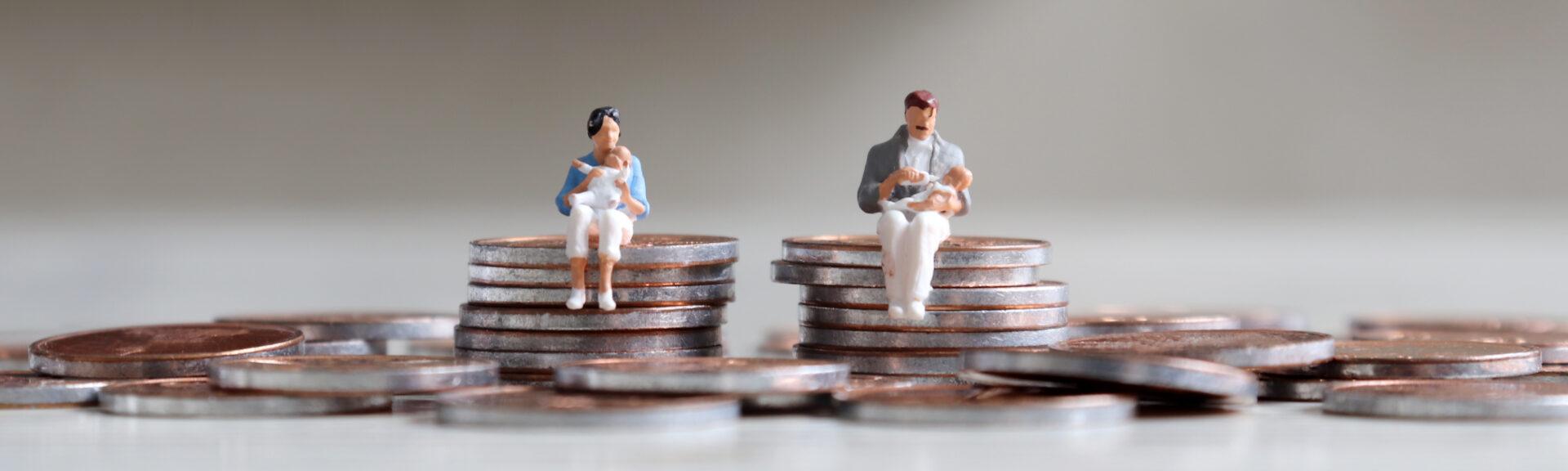 A miniature man and a miniature woman sitting on coins with babys in their arms