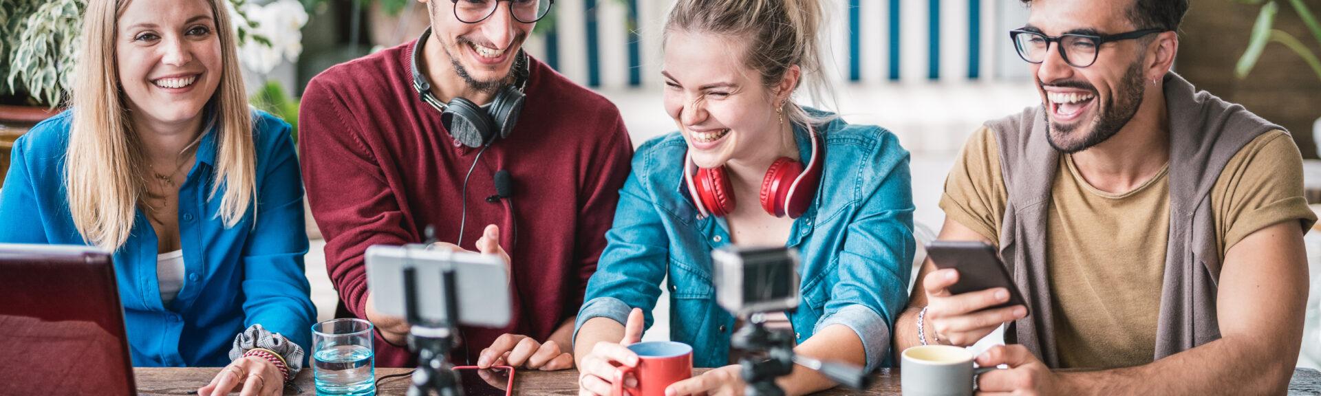 Young friends group sharing info on streaming platform with webcam - Startup marketing concept with millennial guys and girls having fun vlogging live talk feed on social media network - Bright filter