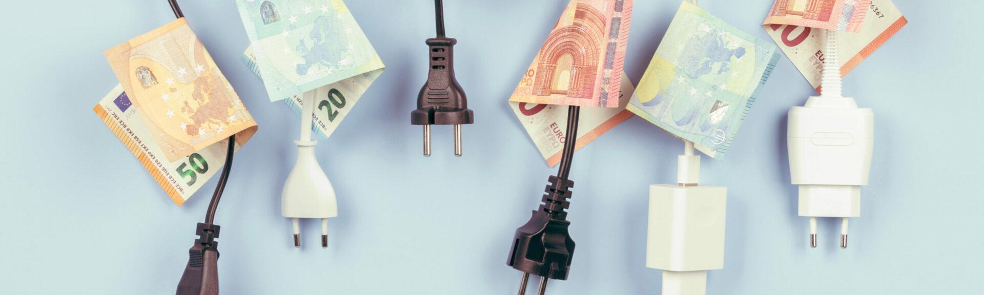 Electric power plugs with Euro banknotes on them hanging on light blue background. Energy efficiency, power consumption, electricity cost, and expensive energy concept