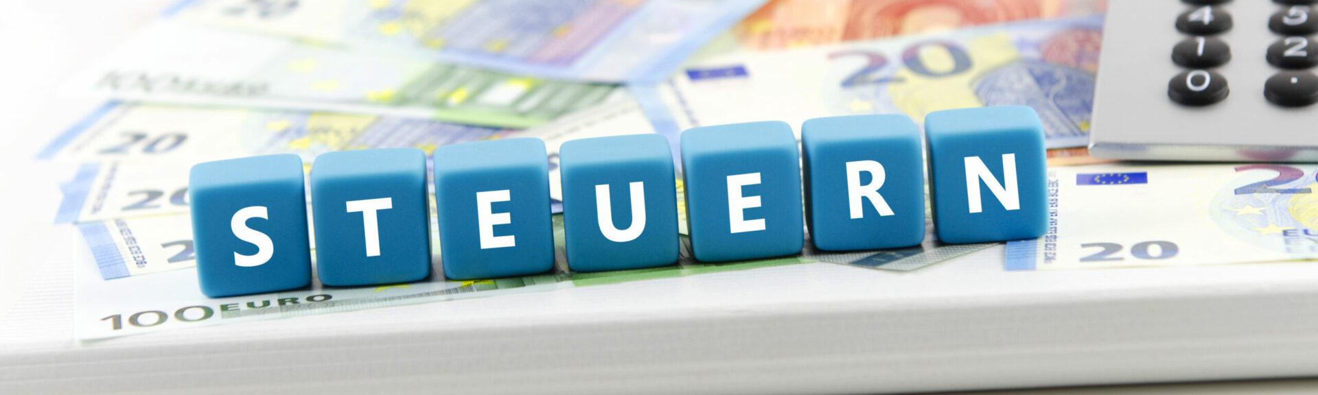 Steuern geschriben auf blöche stehend auf Geldscheinen mit einem Taschenrechner daneben