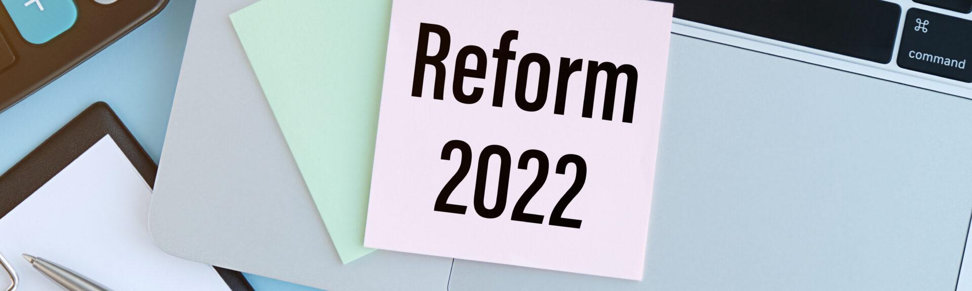 REFORM 2022 text on the paper with laptop, calculator,pen on the blue background.