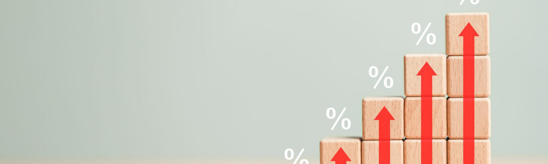 Rising percentage Interest rate financial bar chart with high up arrow and housing mortgage rates on wooden blocks background. Business symbol and economic development success market share concept.