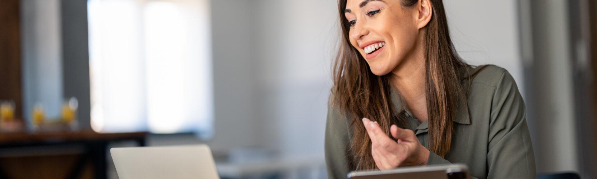Happy confident businesswoman video calling on laptop, working from home. Smiling female business person talking by conference online virtual chat using laptop computer at home office sitting at desk.