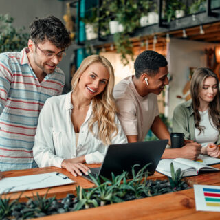 Multiracial creative people in modern office. Group of young business people and senior boss are working together with laptop, tablet, smart phone, notebook, graphs. Successful team in coworking