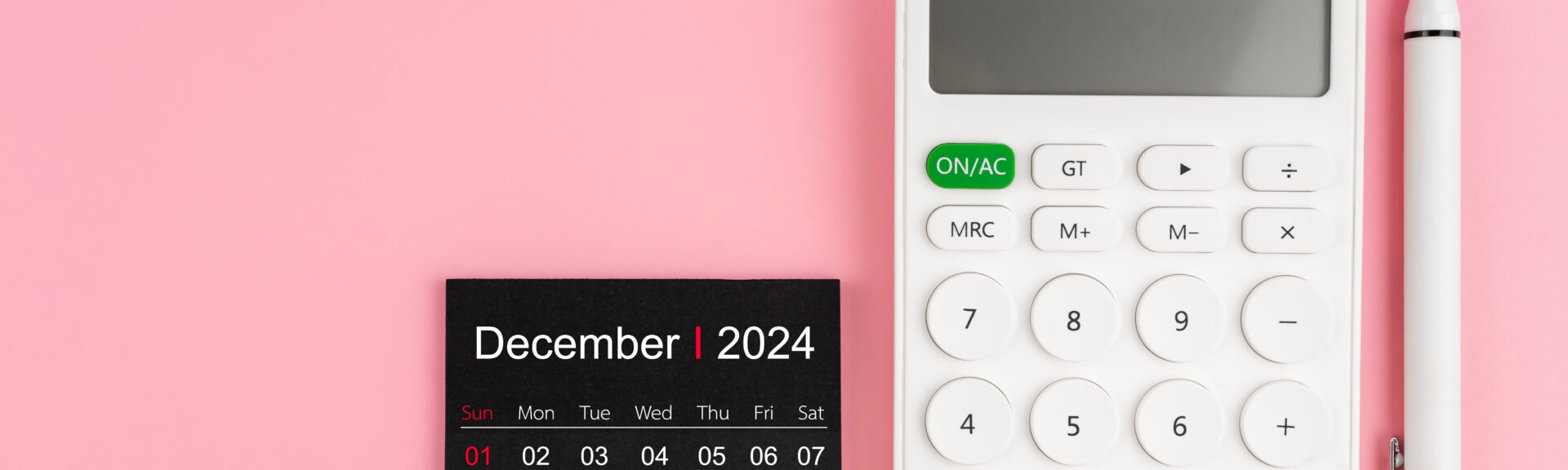 Top view of December 2024 calendar and white calculator with pen on pink background, Position with copy space.