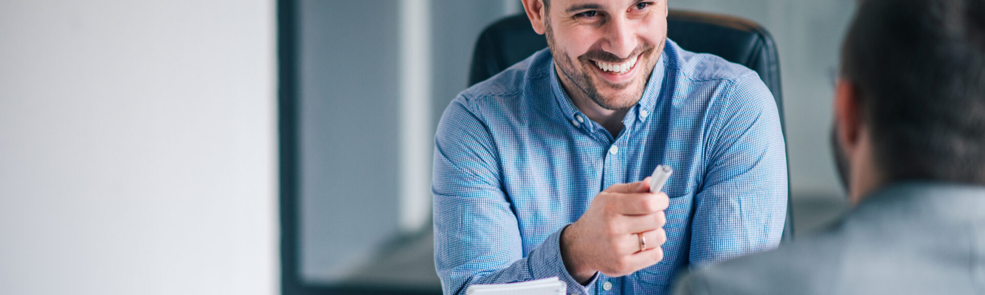 Two smiling man talking in the office.