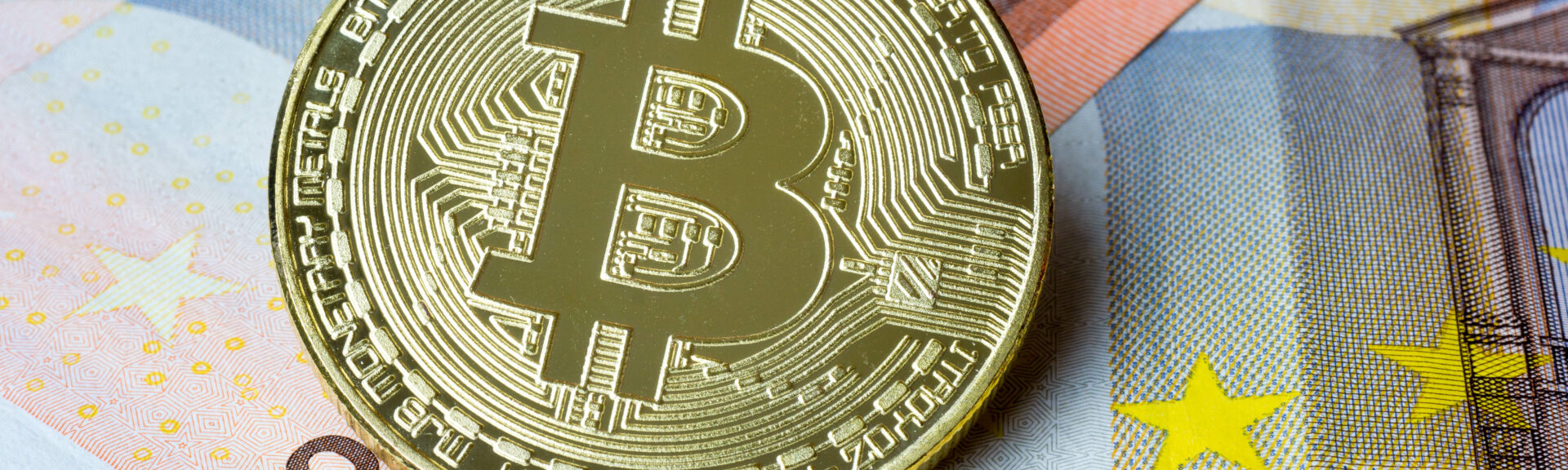 Bitcoin Münze auf Euroscheinen