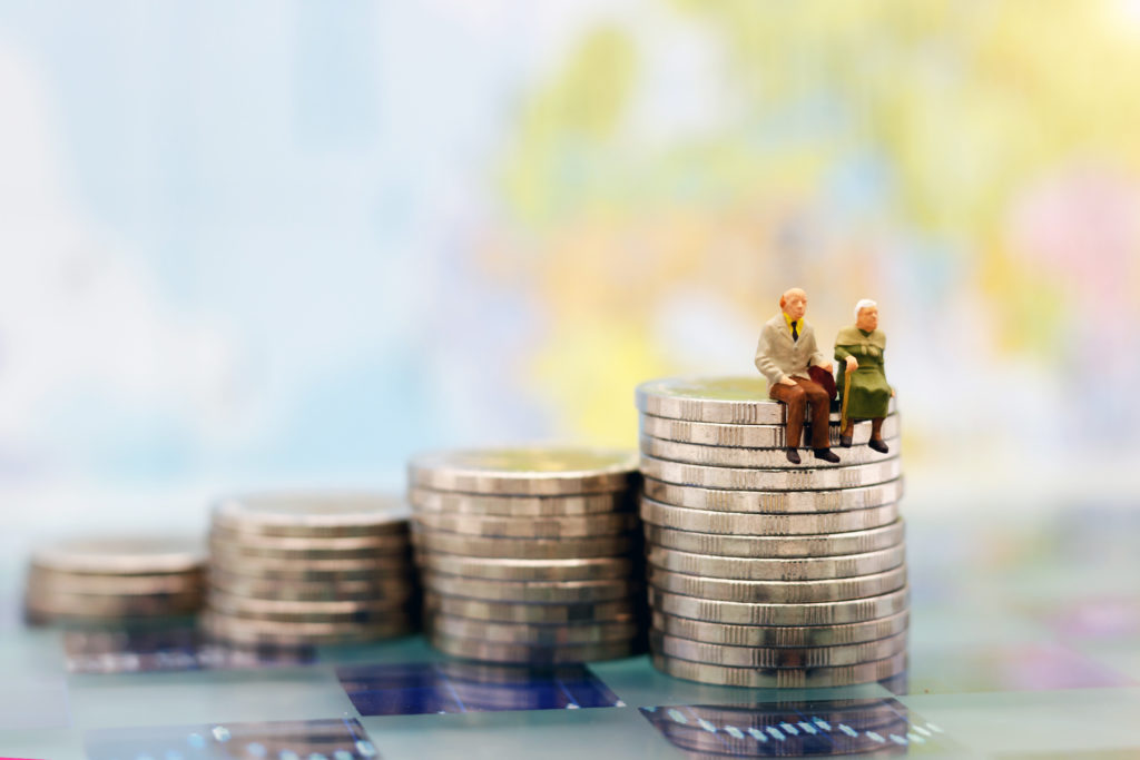 Miniature people: Happy senior couple sitting on coins stack, money saving growth. Retirement, emergency plan and Financial Concept.